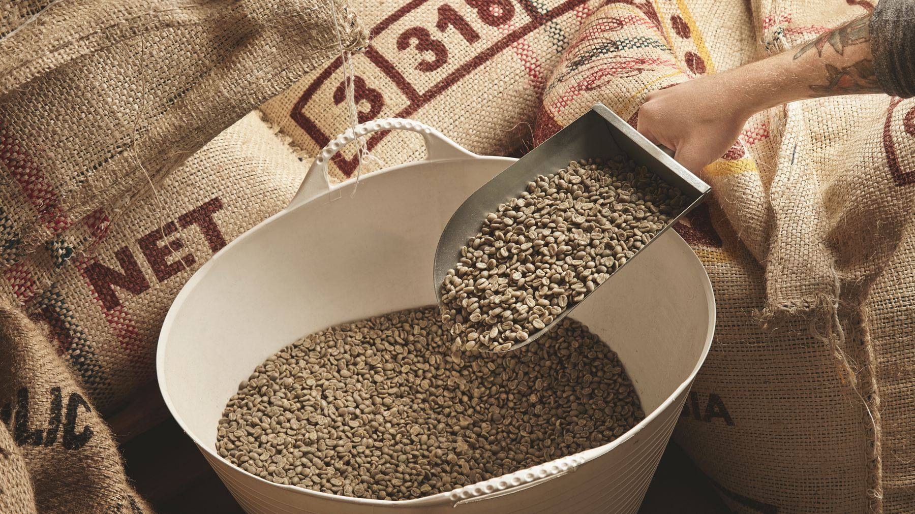 Bulk raw material scooped from jute sacks into a tub